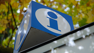 blue on white information icon on a blue cube on top of a building