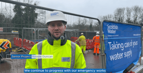 Man wearing construction gear in front of heras fencing on a construction site