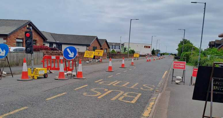 Temporary lights and traffic cones are shown on a residential street