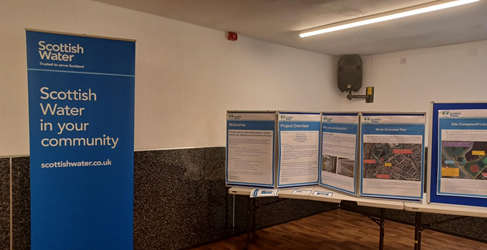 A Scottish Water banner is shown next to information posters on top of a table