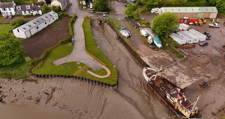 Aerial view of a muddy harbour at low tide with a rusty trawler and moored boats