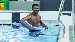 Amanuel Akulu in a swimming pool taking adult swimming lessons as part of the Never Too Late Learn to Swim programme