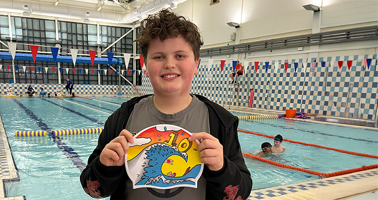 Schoolboy Reuben Norbury holds up his winning cap design at the pool