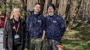 Reservoir Ranger Josh pictured with female from Scottish Fire and Rescue Service on left and male Scottish Water colleague on right. They are outdoors with trees behind them.