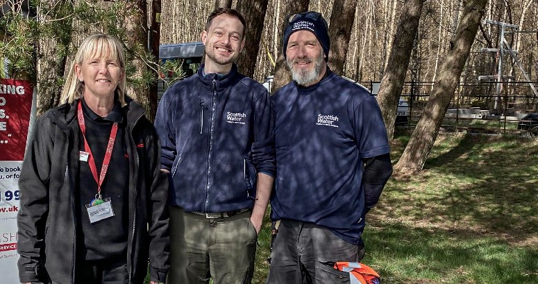 Reservoir Ranger Josh pictured with female from Scottish Fire and Rescue Service on left and male Scottish Water colleague on right. They are outdoors with trees behind them.