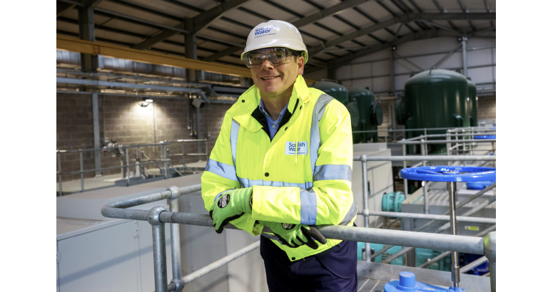 Alex Plant, Scottish Water CEO, in high-visibility jacket in hard hat smiling for camera, situated within water treatment facility