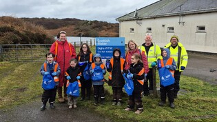 a small class of children visiting a water treatment works on Gigha with their teachers and two Scottish Water employees