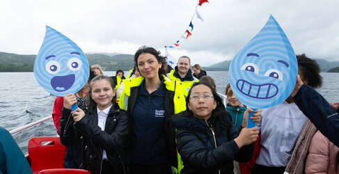 kids on a boat holding a water droplet sign with Scottish Water employee