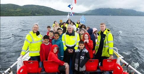 Scottish Water's COO with a group of children holding water droplet signs to launch Generation H2O