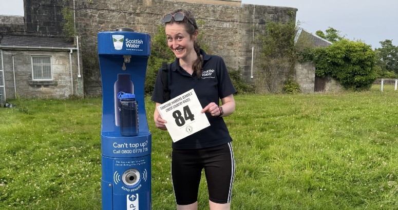 Grace the Ranger at the Milngavie Top Up Tap following her community race. She is holding her number from the race.