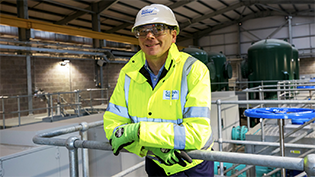 Scottish Water CEO Alex Plant in hi viz and hat leaning on railings inside a new pumping station at Ibrox 