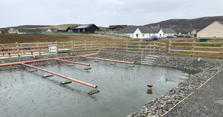 The new aerated reed bed that has been installed as part of Orphir WWTW, with the village beyond