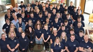 Group of people in matching Scottish Water branded polo shirts posing for a photo indoors