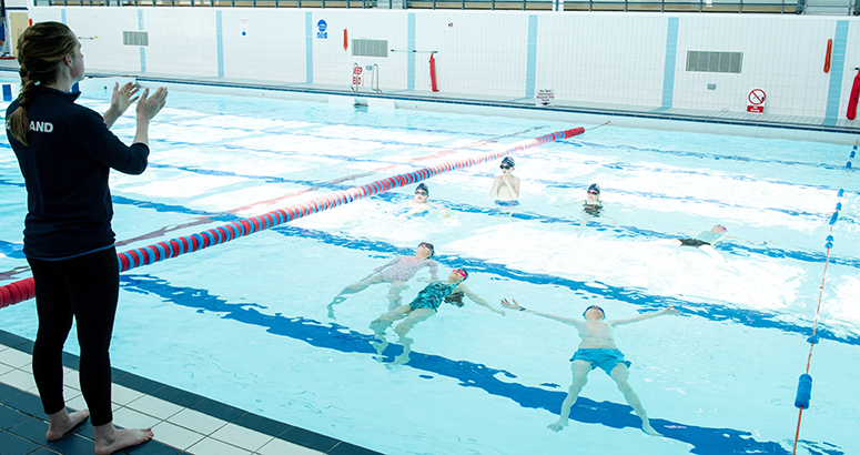 female instructor giving a swimming lesson with children in a swimming pool