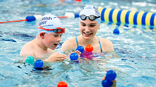 Paralympian swimmer Toni Shaw with a young boy in a swimming pool at a Learnt to Swim lesson