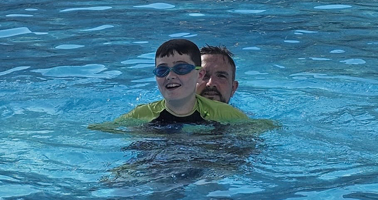 boy with autism and his dad in swimming pool